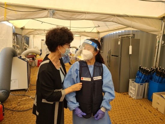 윤석완 부회장(왼쪽)이 선별진료소 의료진에 얼음조끼를 직접 입혀주고 있다​